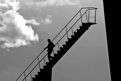 Low angle view of silhouette man standing on staircase against sky