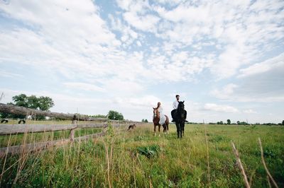 Couple riding horse on field