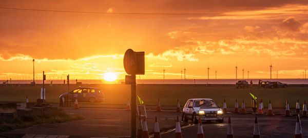 Rally cars on road against sky during sunset