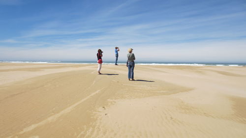 People standing at beach against sky