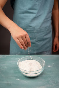 Baker sprinkle salt into the wheat flour, baking ingredient for bread, pizza or pastry dough
