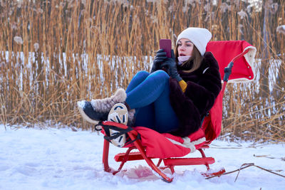 Rear view of woman sitting on snow covered field