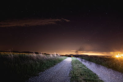 Road amidst field against sky at night