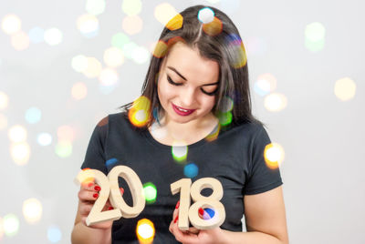 Smiling young woman holding number blocks against white background