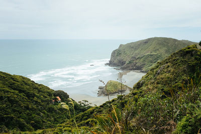 Scenic view of sea by mountains against sky