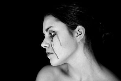 Portrait of young woman against black background