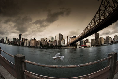 View of city at waterfront against cloudy sky