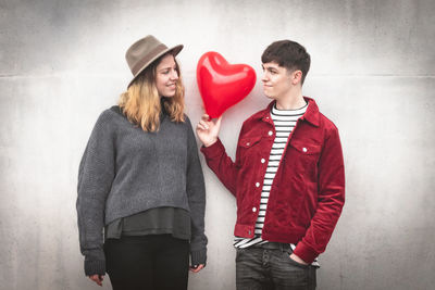 Young couple standing against red wall