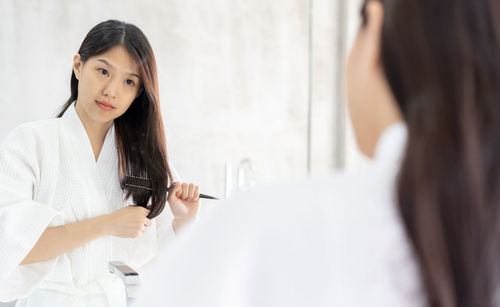 Young woman with arms raised in bathroom