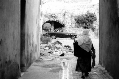 Rear view of woman walking by building