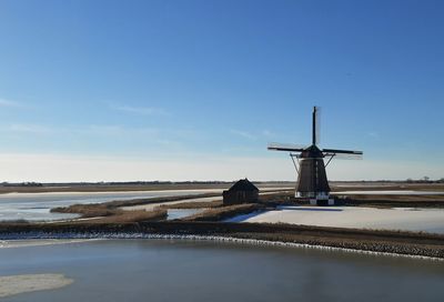 Traditional windmill by sea against sky