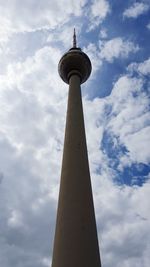 Low angle view of communications tower against cloudy sky