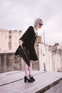 Woman with umbrella standing on canal in city