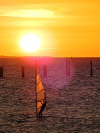 Silhouette person in sea against sky during sunset