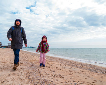 Father daughter walking running on beach. lifestyle real people blue sea sky happy family having fun 