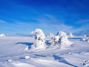 Snow covered landscape against blue sky