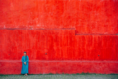 Woman standing against red wall