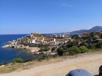 Scenic view of sea and buildings against clear blue sky