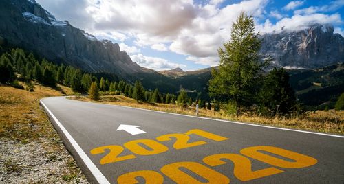 Road sign by trees against sky