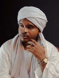 Portrait of young man looking away against black background