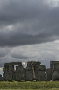 Stone wall on field against cloudy sky