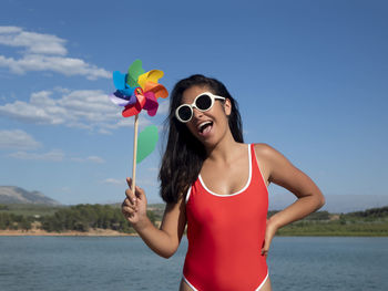 Portrait of woman wearing sunglasses against sea against sky