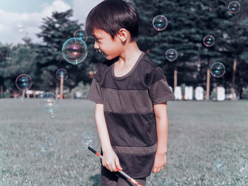 Close-up of boy blowing bubbles in park