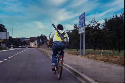 Rear view of man riding bicycle on road