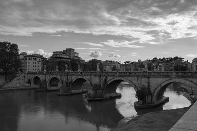 Arch bridge over river against cloudy sky