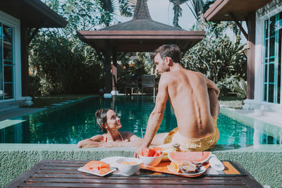 People sitting by swimming pool