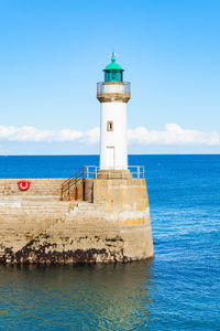 Lighthouse by sea against sky