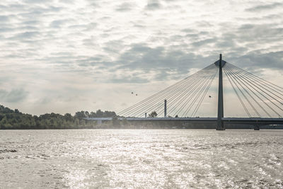 Suspension bridge over river against sky