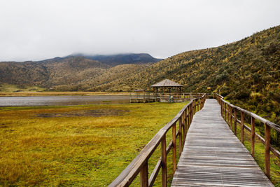 Boardwalk leading towards mountain against sky