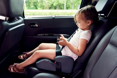 Girl holding mobile phone in car