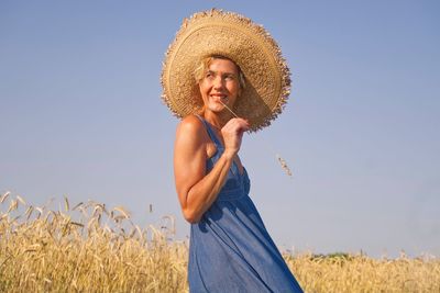 Side view of woman wearing hat standing on land against clear sky