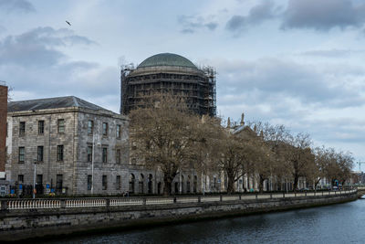 Building by river against cloudy sky