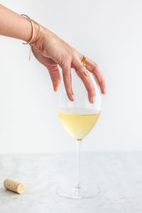 Cropped hand of woman holding drink against white background