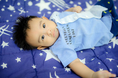 Portrait of cute baby girl lying on bed at home