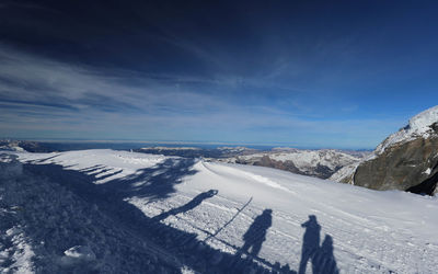 Scenic view of snowcapped mountains against blue sky