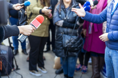 Reporters at news conference or media event, red microphone in the focus