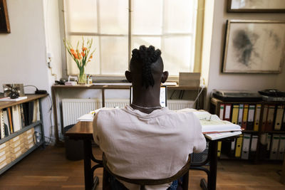 Rear view of businessman working on laptop while sitting at studio