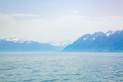 Scenic view of sea and snowcapped mountains against sky