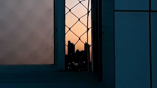 Silhouette of building against sky seen through window