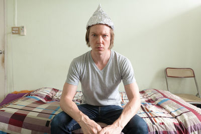 Portrait of smiling man sitting on bed at home