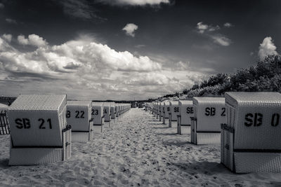 Hooded chairs on beach against sky