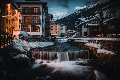 Canal amidst buildings in city during winter