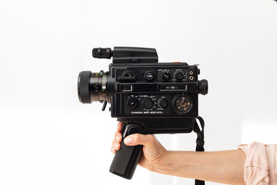 Cropped hand holding camera against white background