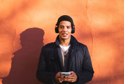 Portrait of smiling young man standing against wall