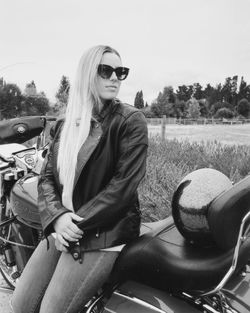 Portrait of young woman wearing sunglasses standing against sky