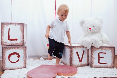 Full length of boy playing with text at home